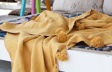 Mustard Pompom blanket on a swing sun bed