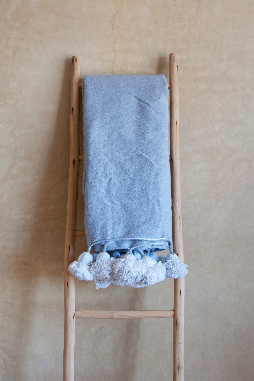Grey bed spread with white pompoms
